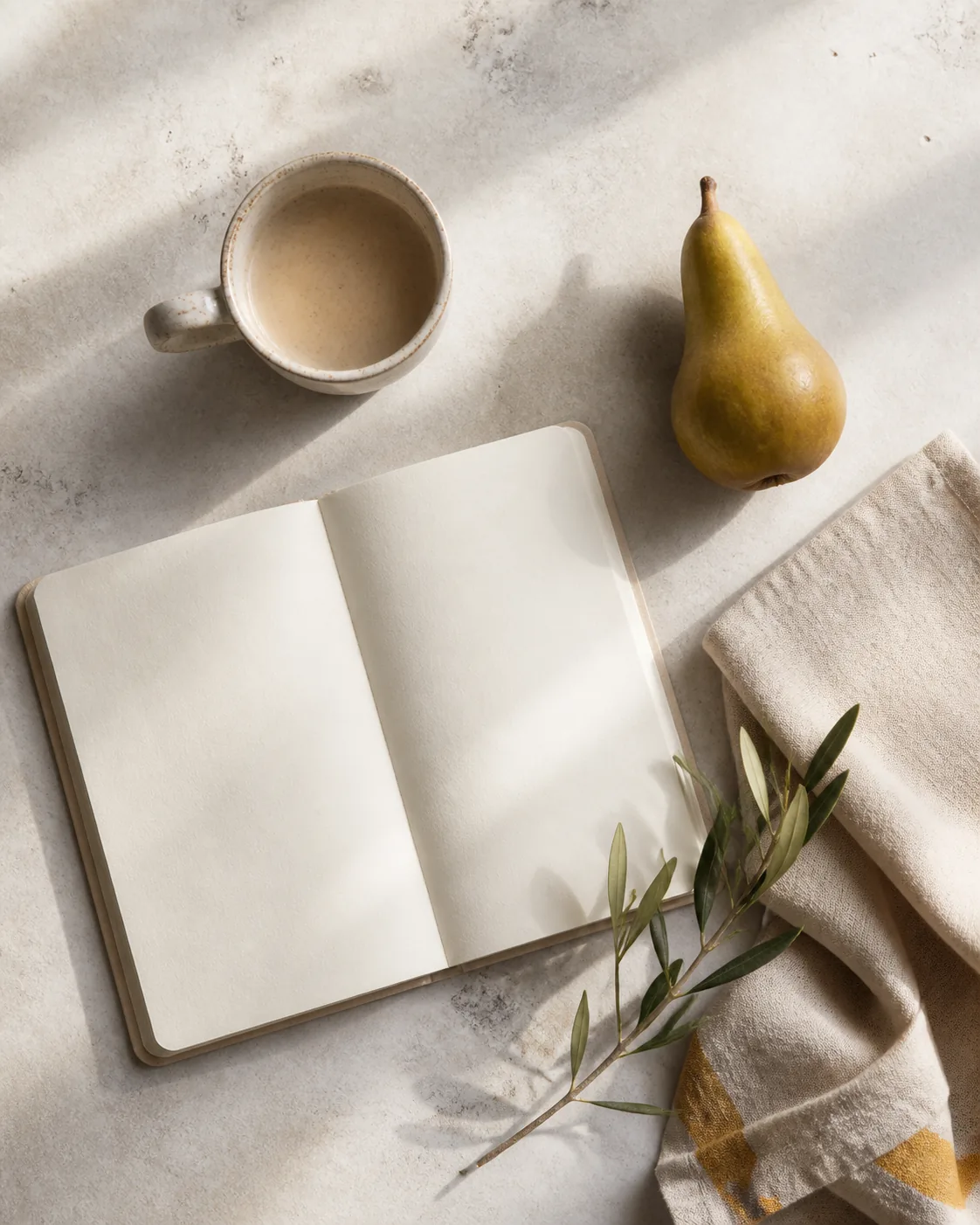 A notebook, ceramic cup, and pear in natural light